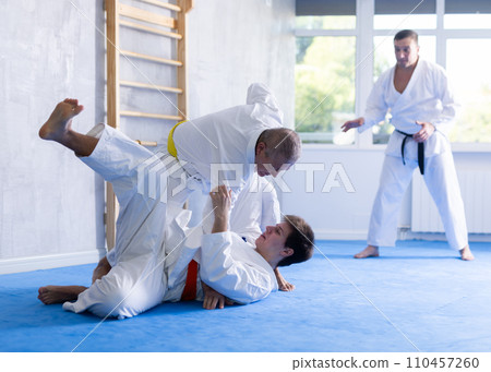 Aged man working on jiu-jitsu techniques in training fight with young rival Aged man working on jiu-jitsu techniques in training fight with young rival 110457260