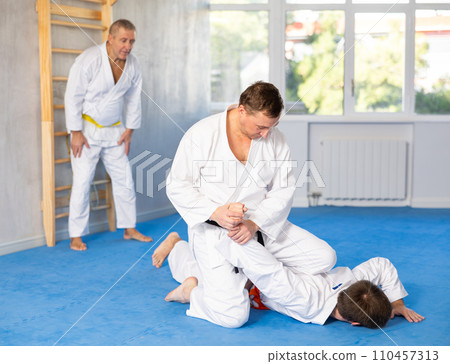 Focused adult jiu-jitsu fighter performing painful armlock during sparring 110457313
