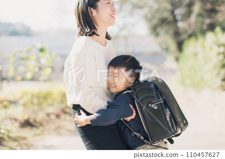 Young mother and boy carrying a school bag 110457627