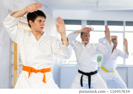 Concentrated guy practicing punches and blocks during martial arts workout 110457634