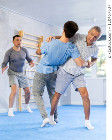Elderly man practicing self-defence techniques in sparring with young opponent 110457637