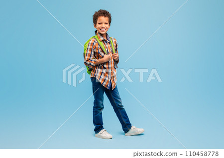 Smiling boy with backpack in plaid shirt, blue background Smiling boy with backpack in plaid shirt, blue background 110458778