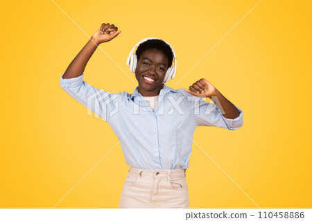 Glad african american young woman student with headphones dance, enjoy music 110458886