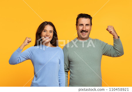 Happy senior european couple winners raise their fists in triumphant gesture Happy senior european couple winners raise their fists in triumphant gesture 110458921