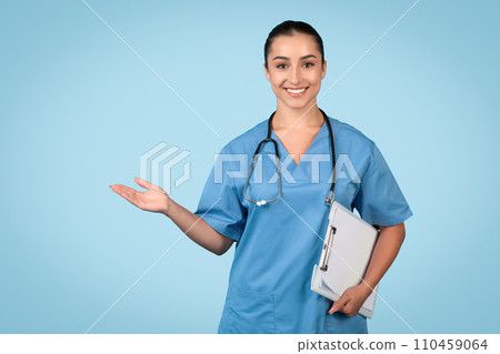 Smiling female nurse in scrubs with clipboard presenting free space Smiling female nurse in scrubs with clipboard presenting free space 110459064