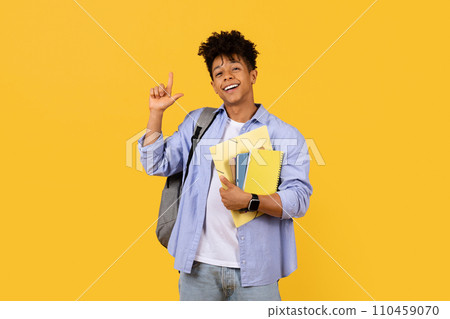 Cheerful student gesturing size with hand on yellow background 110459070
