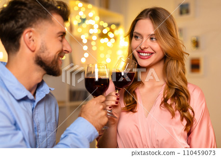 Smiling couple clinking wine glasses, with festive lights Smiling couple clinking wine glasses, with festive lights 110459073