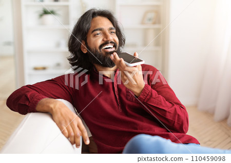 Positive indian guy recording voice mail on smartphone Positive indian guy recording voice mail on smartphone 110459098