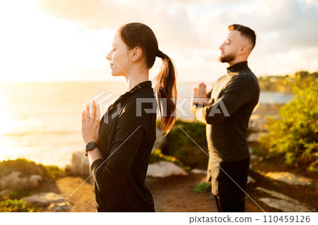Serene man and woman practicing outdoor meditation at sunset 110459126