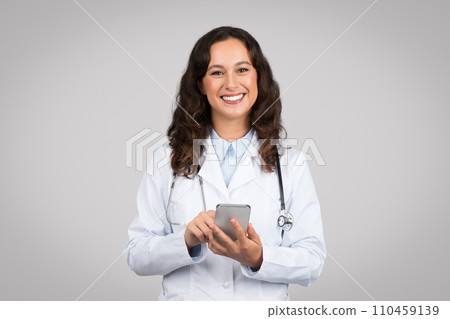 Smiling woman doctor texting on a smartphone 110459139