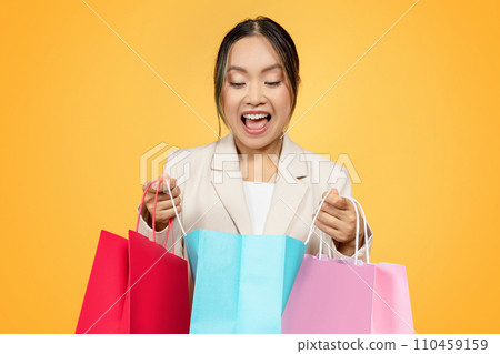Surprised glad young korean lady shopaholic open colorful bags, with purchases enjoy shopping Surprised glad young korean lady shopaholic open colorful bags, with purchases enjoy shopping 110459159