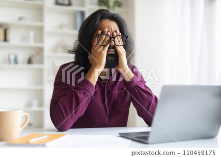 Indian Man Suffering Eyes Strain While Working With Laptop At Home Office 110459175