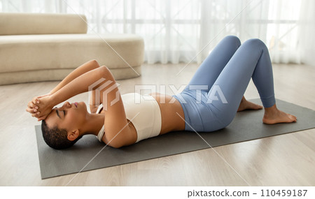 A young latin woman in a serene home setting performs a relaxation exercise 110459187