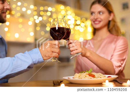 Couple toasting over dinner with a romantic light backdrop Couple toasting over dinner with a romantic light backdrop 110459208