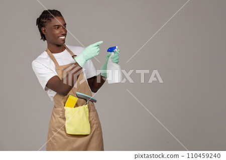 Cleaning Advertisement. Young Black Male Cleaner Holding Detergent Spray And Pointing Aside Cleaning Advertisement. Young Black Male Cleaner Holding Detergent Spray And Pointing Aside 110459240