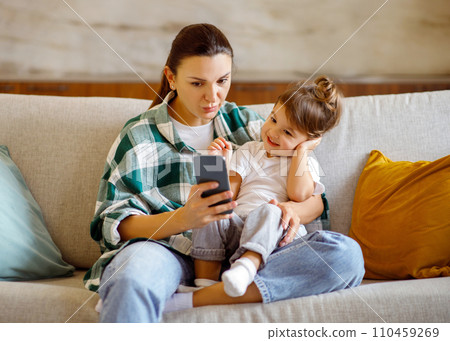 Online Shopping. Cute Little Girl And Her Mom Using Smartphone At Home 110459269