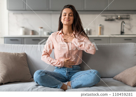 Relaxed young woman meditating on sofa at home Relaxed young woman meditating on sofa at home 110459281