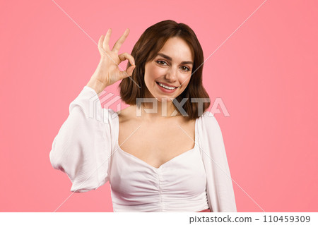 A joyful young woman with short brown hair gives a perfect sign with her hand 110459309