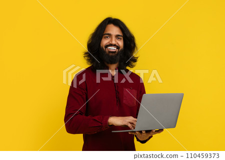 Cheerful young indian guy student using laptop Cheerful young indian guy student using laptop 110459373