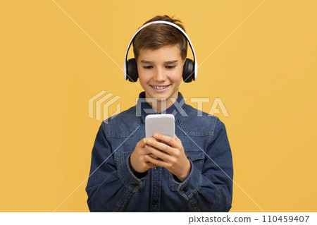 Smiling Teen Boy Wearing Wireless Headphones Using Modern Smartphone, 110459407