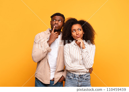 Thoughtful black couple with curious expressions on yellow 110459439