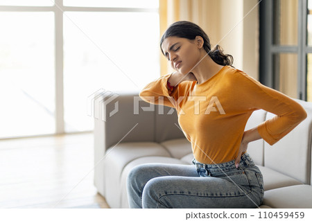 Young Indian Woman Suffering Neck And Back Pain At Home Young Indian Woman Suffering Neck And Back Pain At Home 110459459