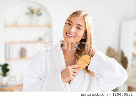 blonde lady applies treatment to hair brushing and styling indoor blonde lady applies treatment to hair brushing and styling indoor 110459531