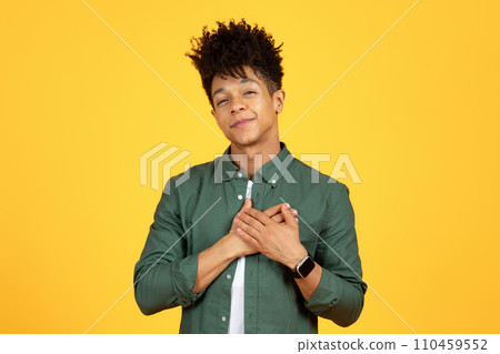 Smiling young black man holding hands over chest 110459552