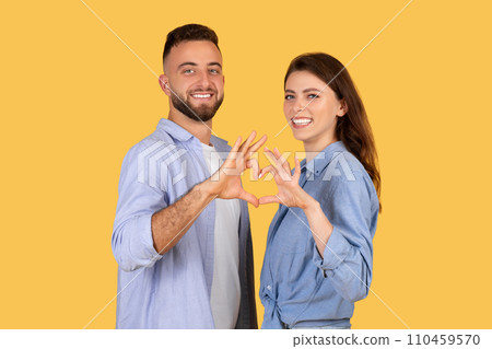 Happy couple forming heart shape with hands, affectionate pose Happy couple forming heart shape with hands, affectionate pose 110459570