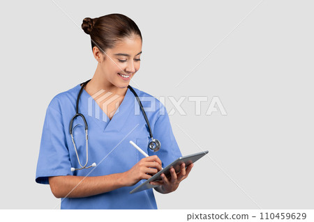 Engaged Caucasian millennial medical professional in blue scrubs using a digital tablet Engaged Caucasian millennial medical professional in blue scrubs using a digital tablet 110459629