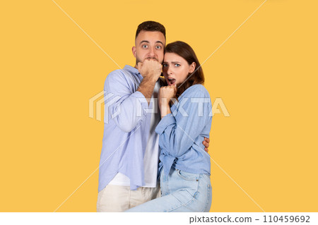 Surprised couple with man covering his mouth and woman looking shocked Surprised couple with man covering his mouth and woman looking shocked 110459692
