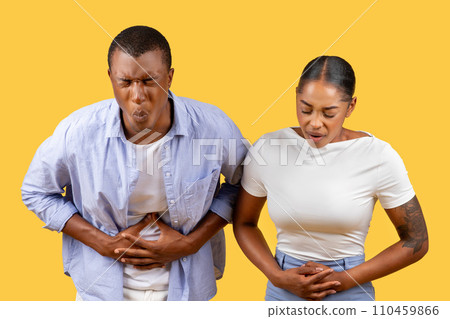 African american couple with stomach pain, uncomfortable expressions, yellow background 110459866