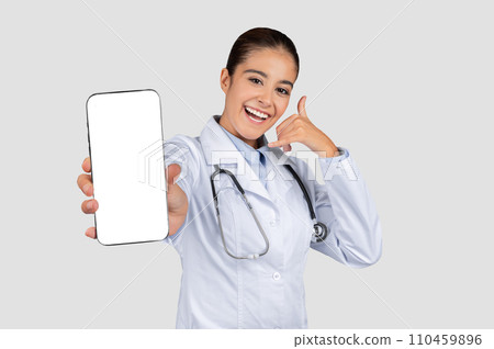 Smiling caucasian millennial doctor in white coat, show phone with empty screen and call me 110459896