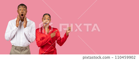 Shocked black man and surprised woman pointing, wide pink background 110459902
