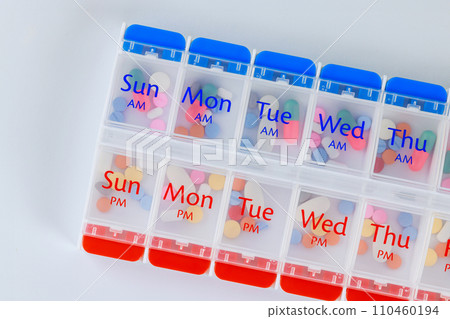 Organizer daily pill dispenser box with medications capsules on white isolated background. Organizer daily pill dispenser box with medications capsules on white isolated background. 110460194