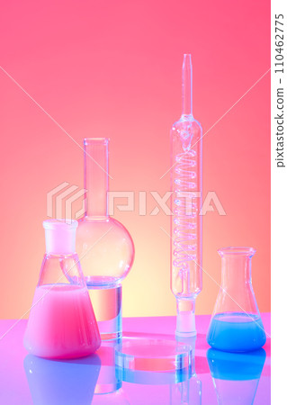 Erlenmeyer flasks containing color liquid decorated with boiling flask and spiral condenser tube on color gradient background. Laboratory concept with blank space for display product 110462775
