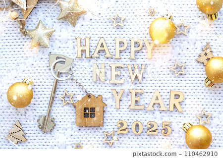 House key with keychain cottage on festive background with stars, lights of garlands. New Year 2025 wooden letters, greeting card. Purchase, construction, relocation, mortgage, insurance 110462910