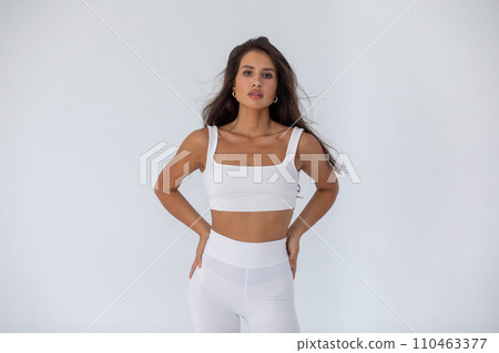 Beautiful brunette girl in a white top and tights posing on white background 110463377