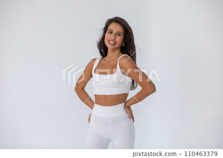 Beautiful brunette girl in a white top and tights posing on white background 110463379