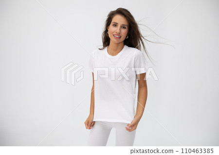 Beautiful brunette girl in a white T-shirt posing on white background Beautiful brunette girl in a white T-shirt posing on white background 110463385