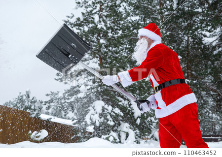 Santa Claus cleans snow with shovel in winter outdoors after a snowfall. Cleaning the streets in the village, clearing the passage for cars, difficult weather conditions for Christmas and New Year Santa Claus cleans snow with shovel in winter outdoors after a snowfall. Cleaning the streets in the village, clearing the passage for cars, difficult weather conditions for Christmas and New Year 110463452
