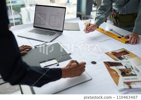 Hands of architects working on building blueprint for client 110463487