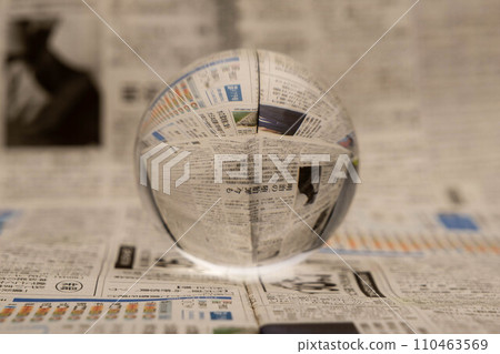 A glass globe reveals the letters inside, with a newspaper in the background. A glass globe reveals the letters inside, with a newspaper in the background. 110463569