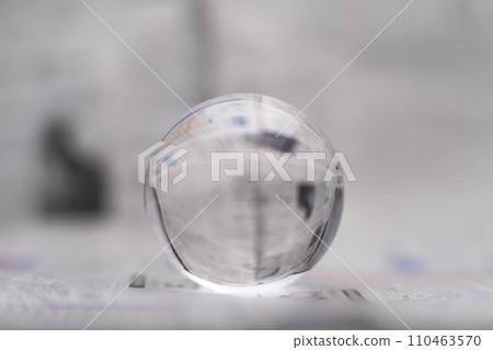 A glass globe reveals the letters inside, with a newspaper in the background. A glass globe reveals the letters inside, with a newspaper in the background. 110463570