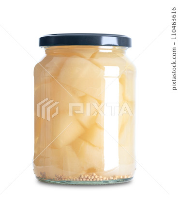 Mustard pickles, sweet and sour pickled gherkins, in a glass jar. Cucumber chunks, pasteurized and preserved in a brine of vinegar, salt, sugar and mustard seeds. A side dish. Close-up, front view. 110463616