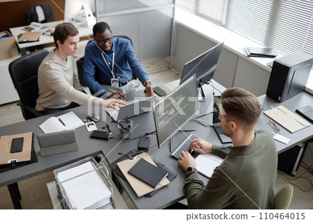 High angle shot of busy IT professionals sitting at office desks while developing cybersecurity protocols during workday in modern IT company High angle shot of busy IT professionals sitting at office desks while developing cybersecurity protocols during workday in modern IT company 110464015