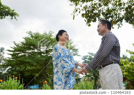 Smiling senior Vietnamese man and woman holding hands and looking at each other Smiling senior Vietnamese man and woman holding hands and looking at each other 110464163
