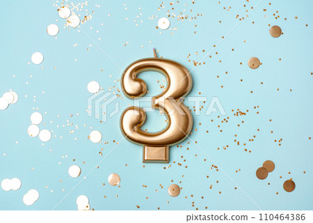 Gold candle in the form of number three. 110464386