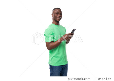 young happy friendly american man dressed in green t-shirt and jeans chatting on the phone 110465156