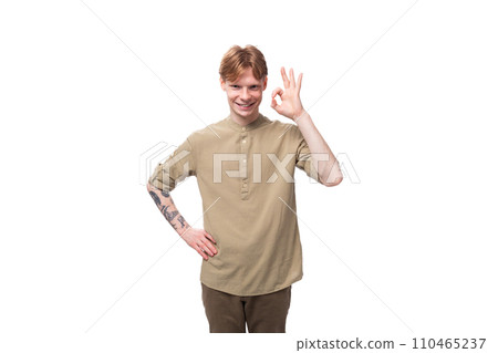 a young European man with red golden hair dressed in a light brown shirt gesticulates on a white 110465237